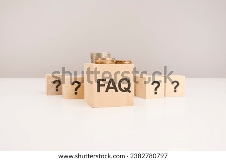 FAQ concept. wooden block with FAQ - Frequency Asked Questions - symbol and coins on gray background