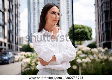 Photo of smart charming lady sales manager dressed white shirt eyewear arm hand chin choosing apartment outdoors urban town street