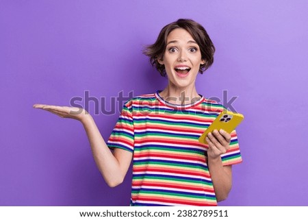 Portrait of astonished attractive person use smart phone arm hold show empty space offer isolated on purple color background