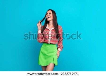 Photo of charming young girlfriend laughing playful touching hair looking empty space new brand store isolated on cyan color background