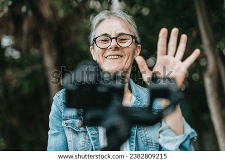 Joyful woman opening a live stream on social app greeting her followers and asking questions. Royalty-Free Stock Photo #2382809215