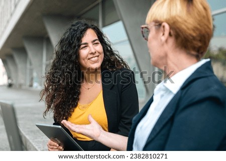 Business people in financial district, diverse colleagues working near office building using laptop Royalty-Free Stock Photo #2382810271