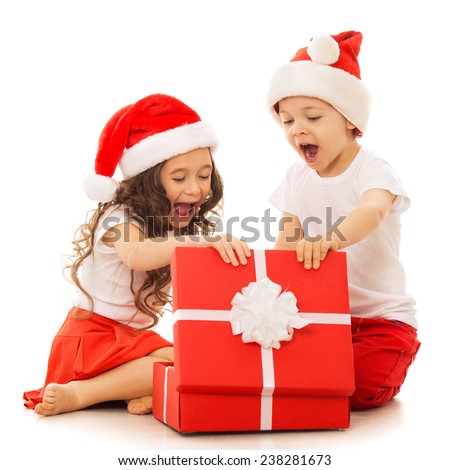 Happy kids in Santa hat opening a gift box. Isolated on white background.  With colorful lights from Christmas tree on background. Holidays, christmas, new year, x-mas concept.