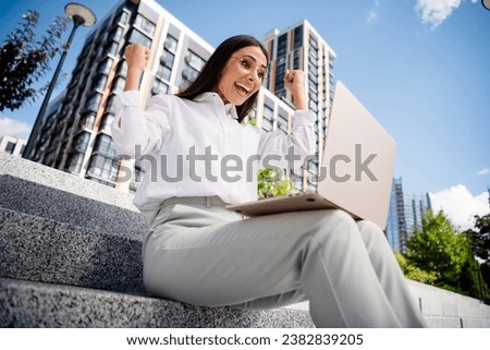 Photo of positive joyful glad lady brunette sitting center modern buildings town speaking video call sunny outdoors