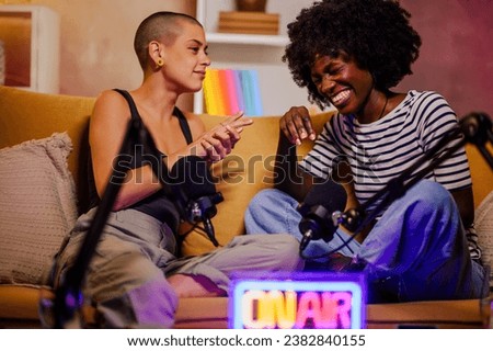 Portrait of caucasian female content creator interviewing famous african american woman in a studio. Recording internet podcast and using professional audio equipment. Focus on a black woman laughing.