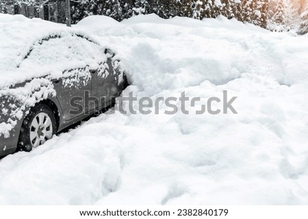 City street driveway parking lot spot with small car covered snow stuck trapped after heavy blizzard snowfall winter day by big snowy pile. Snowdrifts and freezed vehicles. Extreme weather conditions Royalty-Free Stock Photo #2382840179