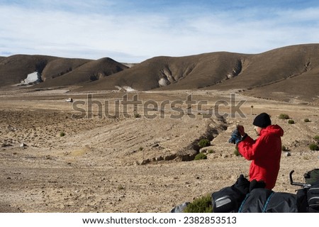 Young man photographing with cell phone inhospitable landscape in Bolivia Royalty-Free Stock Photo #2382853513