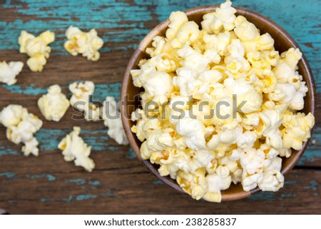 Fresh popcorn in bowl on white wooden table. Selective focus. 
