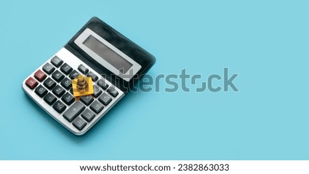 Concept of under construction or fixing for financial, loan, or budget. Safety cone or traffic cone over a calculator on blue background with copy space.