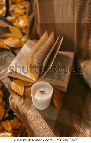 Candle and open book in nature, autumn concept.
