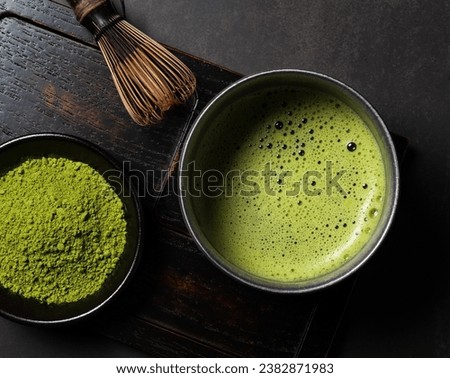 Matcha powder and green tea on dark background. Chasen (tea whisk). View from above.