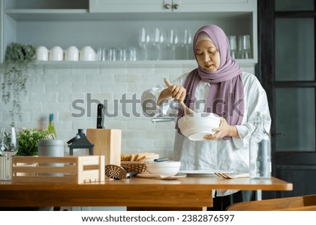 A Muslim woman is preparing to cook breakfast for her family. At the beautiful kitchen in her house, having fun woman with hijab preparing dinner, Islamic woman Enjoying Doing Homemade.