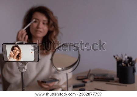 Caucasian woman leads an online make-up lesson for herself on her mobile phone
