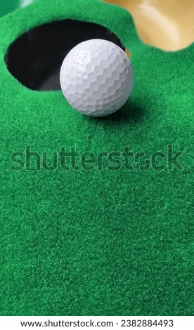 A picture of a golf ball on a green artificial grass surface used for putting practice.