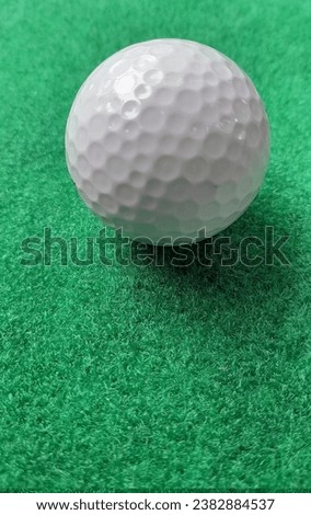 A picture of a golf ball on a green artificial grass surface used for putting practice.