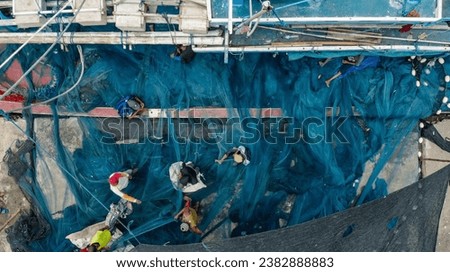 a picture of fishermen repairing fishing nets on the side of the dock Royalty-Free Stock Photo #2382888883