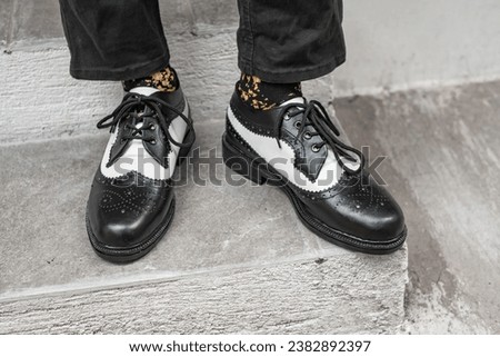 The young man wore a classic two-tone genuine leather brogue, vintage brogue wingtips that were shiny and ready to hang out on a sunny day. Royalty-Free Stock Photo #2382892397