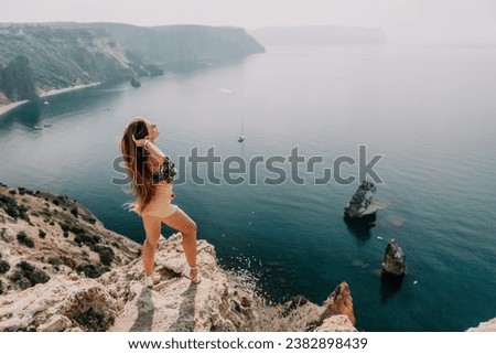 Woman travel sea. Happy tourist enjoy taking picture outdoors for memories. Woman traveler looks at the edge of the cliff on the sea bay of mountains, sharing travel adventure journey