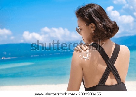 Woman applying sunscreen and taking care of her skin to protect her skin from UV rays She applied sunscreen to her shoulders and body. The sun symbol is a very sunny background. Health concept Royalty-Free Stock Photo #2382909455