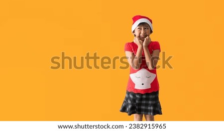 Christmas girl in santa hat and Looking surprise posing, isolated on yellow background