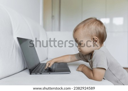 A little boy works on a laptop, presses buttons in a room at home. A small programmer, the concept of early development and online education. High quality photo