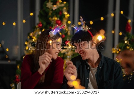 man and woman holding sparkler fireworks in a party with Christmas tree. young couple Asian people enjoy celebrating Christmas and New Year. happy and celebrate with food wine and friendship for love,