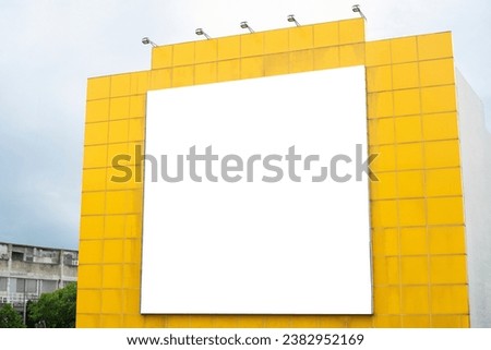 A large billboard is mounted on a backdrop with five spotlights on a yellow background.