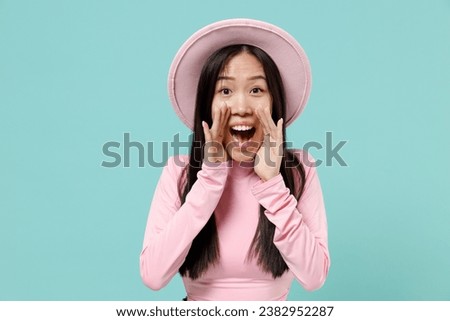 Promoter young woman of Asian ethnicity wear pink clothes hat scream hot news about sales discount with hands isolated on pastel blue color background studio portrait. People emotion lifestyle concept