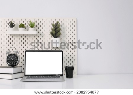 Laptop with blank white screen on office desk.