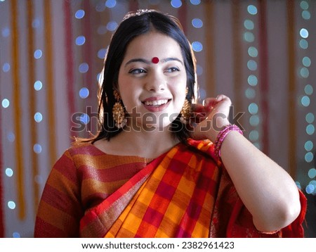 Beautiful Indian Bengali woman dressed in traditional outfit posing for the camera on the occasion of Diwali - Deepawali . A young female dressed in a check print saree - Navratri, Hindu festival Royalty-Free Stock Photo #2382961423