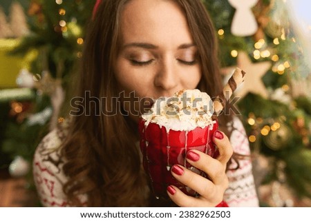 Christmas time. Closeup on modern female with festive hot chocolate cocktail near Christmas tree in the modern house. Royalty-Free Stock Photo #2382962503
