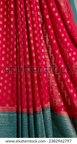 The photo shows a close-up of a res saree with gold polka dots. The saree is made of a soft, flowing fabric and the polka dots are small and evenly spaced. The saree is draped over a stand