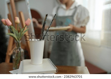 Young female student studying in the art studio Learn how to draw landscapes Mixing watercolors to create art on cardboard design on canvas Develop your art drawing skills with hobby studio activities