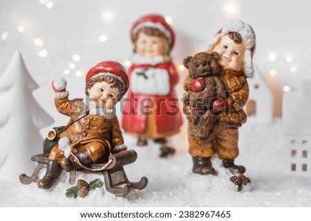 Retro Christmas card with cute figures of children on a wooden sled on a snowy background. Beautiful bokeh. The concept of the winter holiday new year 2024.