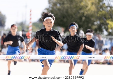 Elementary school boy running in a footrace at a sports day Royalty-Free Stock Photo #2382969993
