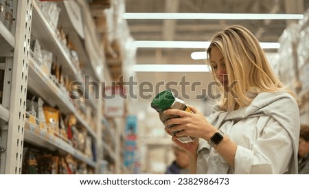 40s lady buying coffee jar grocery shop. Woman pick up latte pack. Girl take item put cart. Person visit food market. Instant coffee lover choose package. Black coffe drinks row store. Energy beverage Royalty-Free Stock Photo #2382986473