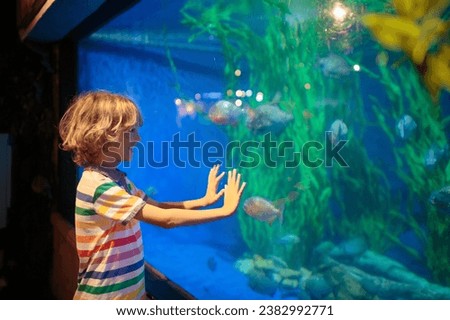 Family in aquarium. Kids watch tropical fish, marine life. Child looking at sea animals in large oceanarium. Ocean life museum. School or vacation day trip to aqua park. Royalty-Free Stock Photo #2382992771
