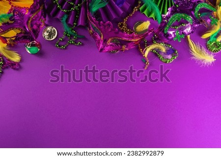 Mardi Gras colorful holiday greeting card background with festival masquerade accessories, decor, carnival mask, beads, feathers, fan on bright background traditional yellow purple green colors Royalty-Free Stock Photo #2382992879