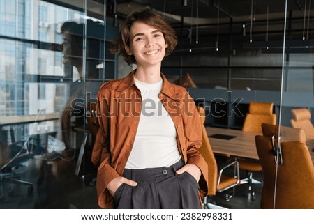 Portrait of young confident woman, start-up manager in office, posing with confidence, looking self-assured, wearing casual, informal clothes. Royalty-Free Stock Photo #2382998331