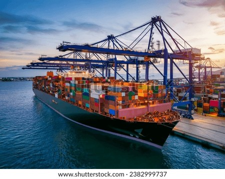 A large container cargo ship is beeing loaded in a commercial dock during sunset Royalty-Free Stock Photo #2382999737