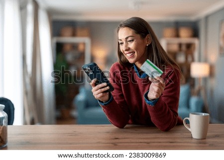 Happy young woman using smart phone shopping online with a credit card. Royalty-Free Stock Photo #2383009869