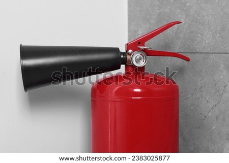Red fire extinguisher in corner, closeup view