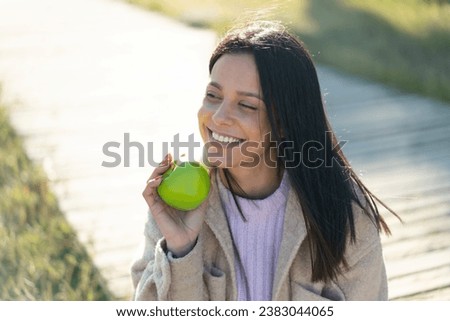 Young woman at outdoors holding an apple with happy expression