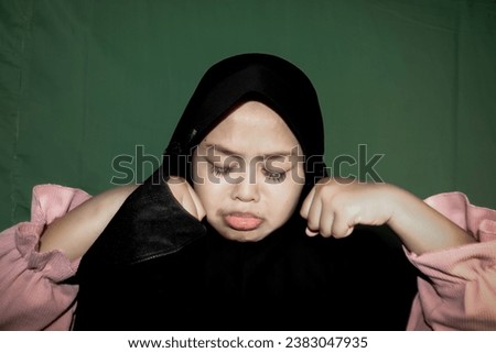 Muslim girl wearing a black hijab with a sad expression and crying with both hands clenched into fists