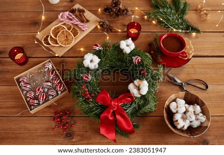 winter holidays, diy and hobby concept - close up of christmas fir wreath making stuff, decorations and hot chocolate on wooden table