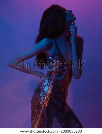 Stylish female model in bright colorful lights posing in studio. Portrait of a beautiful girl with fashionable shining makeup. Beautiful jewelry and accessories. Neon color. Blur portrait