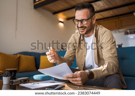 One man mature caucasian male work at home hold paper document sign insurance contract or read report enjoy good news in letter receive official paper about tax refund credit loan approval Royalty-Free Stock Photo #2383074449