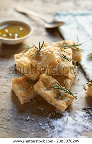 Tasty and healthy rosemary focaccia bread composition with salt, oil and leaves. Typical salty flat bread with rosemary made in Liguria, Italy. Italian focaccia bread with herb in slices.  Royalty-Free Stock Photo #2383078249