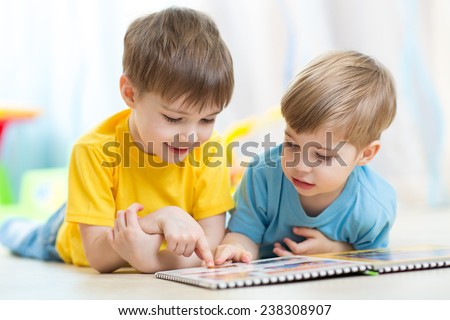 two children looking at book in playschool or nursery