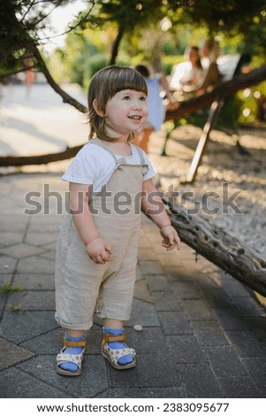 A child of 1 2 3 years old in overalls walks in the park at sunset. One in the frame Royalty-Free Stock Photo #2383095677